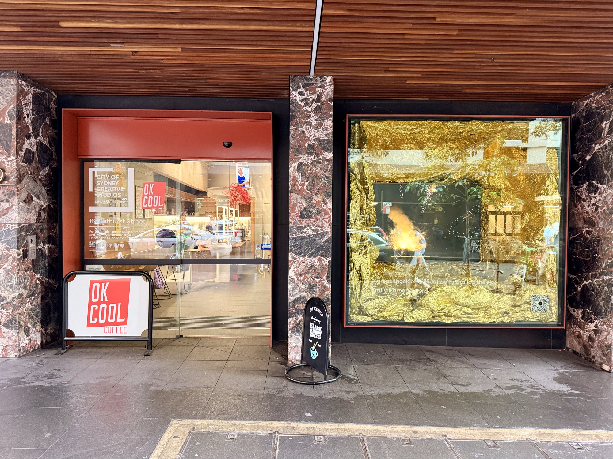 A glass street-level entrance framed by polished stone columns, with an art display in the window