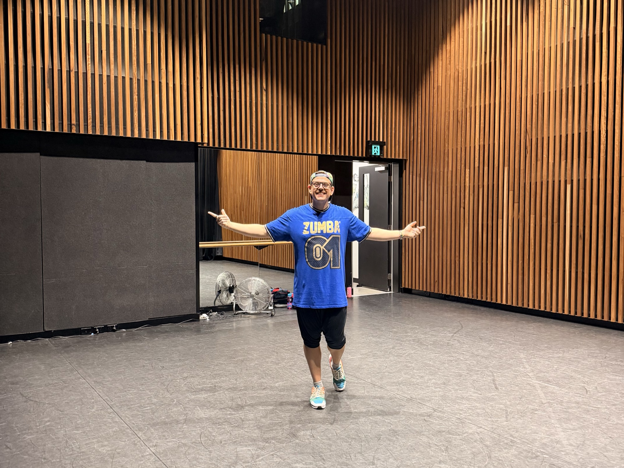 Pawel stands in the middle of an empty wood-panelled studio, arms flung wide and smiling